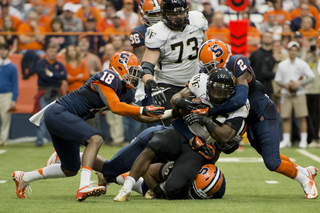 (From left) Syracuse defensive backs Darius Kelly and Wayne Morgan converge to bring down WFU tailback Josh Harris.