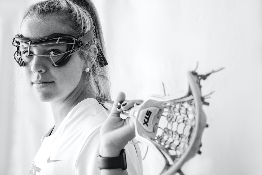 Megan Carney looks toward the camera while holding a lacrosse stick